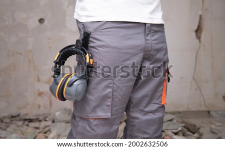 Unrecognizable builder with hearing protection hanging from the trousers. Safety at work concept. Royalty-Free Stock Photo #2002632506