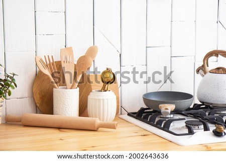 Kitchen utensils and wooden dishes on a wooden shelf Royalty-Free Stock Photo #2002643636