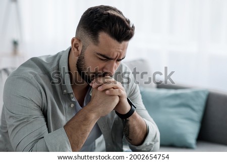 Unhappy depressed caucasian handsome bearded man crying in living room couch, feeling desperate and lonely, isolated at home. In stressed from work, unemployment, anxiety, heartbroken and depression Royalty-Free Stock Photo #2002654754