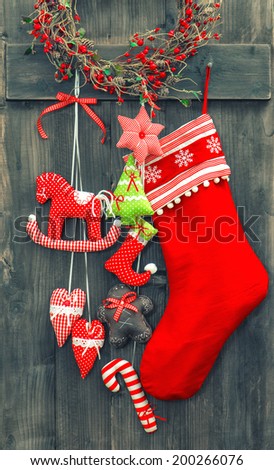 christmas decoration santa's sock and handmade toys over rustic wooden background. nostalgic retro style toned picture