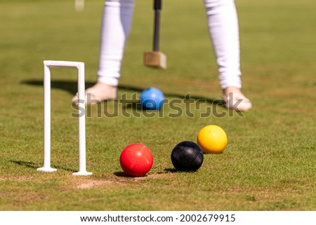 a young woman is playing croquet on a lawn Royalty-Free Stock Photo #2002679915