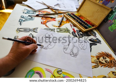 The animator draws with a pencil and draws characters from cartoons, comics or puppet shows. Preparing to make a doll. The designer creates sketches. Comics, cartoons, puppet theater