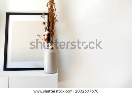 Empty wooden photo,picture frame mock-up with white vase and stylish plant near white wall on table, Copy space modern decoration interior space for text