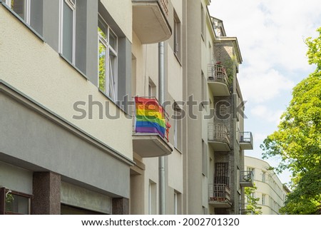 A cheerful rainbow LGBT flag hangs on the balcony of a multi-storey building. The LGBT flag hangs on the facade of the building. The concept of equality and human rights