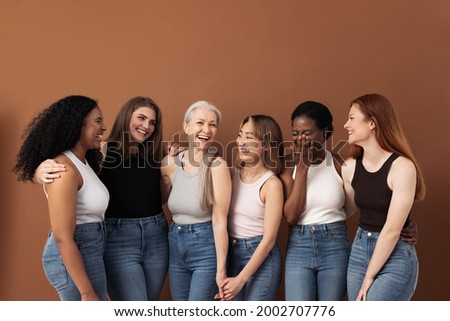 Stylish women of different ages having fun while wearing jeans and undershirts over brown background Royalty-Free Stock Photo #2002707776