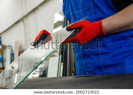 Glass factory, the glazier holds a piece of glass in his hands  Royalty-Free Stock Photo #2002723022