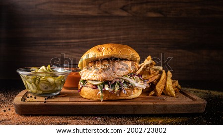 Smoked Salmon Burger on a wooden background with pickles and potatoes