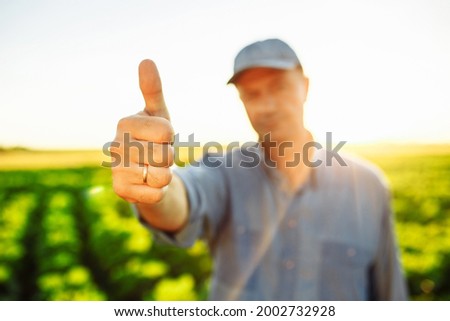 Man farmer shows thumb up with his hand. Agronomist approves good season harvest by like sign. New crop and fruitful agricultural year for trading and harvesting