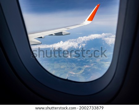 View of Earth and clouds from a window of the flying plane