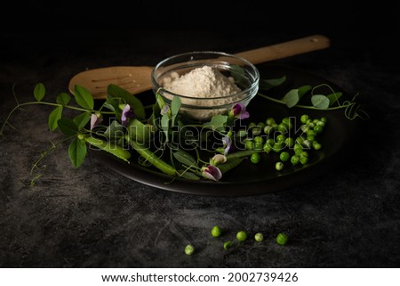Peas and details such as flowers, pods, tendrils but also pea flour and the raw vegetables, dark and moody photography of healthy food with black background

