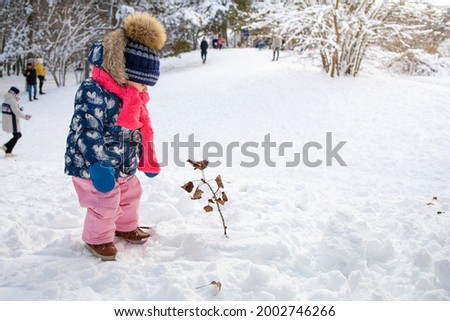 Coming winter, the toddler plays in the snow outside the room. Concept of winter entertainment outside the premises.  Royalty-Free Stock Photo #2002746266