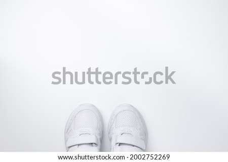 flat lay two white sneakers partially located at the bottom in the center with free space for text isolated on a white background.