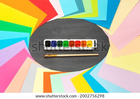 Paints and brushes for painting on  black school board. Colorful craft paper.  

Flat lay, top view, copy space concept.
