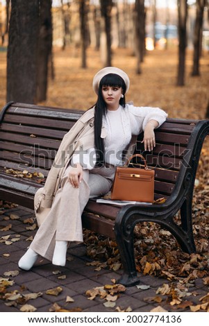 Picture of beautiful woman goes for a walk to the autumn park