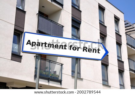 Arrow shaped sign board against the apartment building with the inscription Apartment for Rent