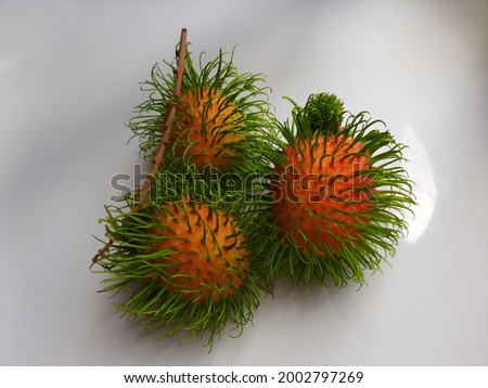 Three rambutan fruit on the white plate with selective focus,litte grain and little noise.