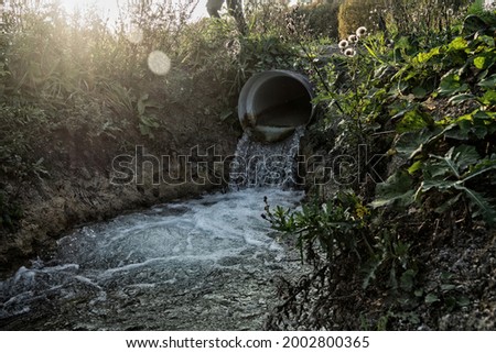 Road culvert in the fall. Water runoff after rain Royalty-Free Stock Photo #2002800365