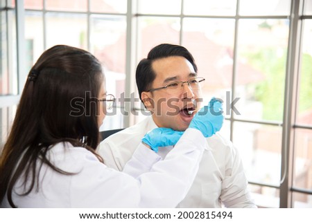 Dentist is putting gauze in her patient mouth, trying to stop wound from bleeding.medical and healthcare concept.