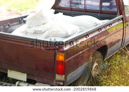 Concept : car accident on wet slippery floor. Blurred  motion photo of  old pick- up car carry overload weight of white sacks that make the car's wheels stuck and sunk on slippery muddy soil ground.  
