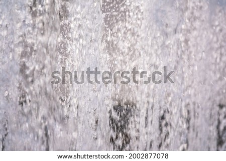 Water splashes from fountain on dark background. Natural texture of only water of fountain. High waves effect in hot summer with copy space. Water sprays in sunny day close-up.