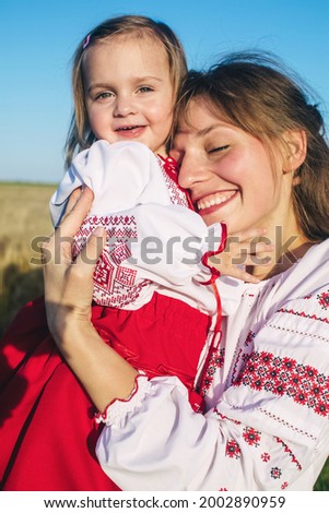 A family in a poppy field dressed in a national Ukrainian costume. Mom, dad and twin girls in embroidered shirts frolic on sunny day. Concept of a happy childhood, history and togetherness