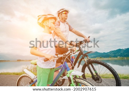 Father and son ride, cycling their bikes together, on sunny day, Happy family in helmets is riding bikes having fun.