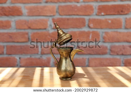 Copper pitcher made for decoration. There is a brick wall in the background of the picture.