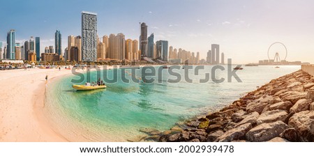 Wide panorama of the Persian Gulf with sandy beach and Bluewaters Island with the worlds famous largest Ferris wheel Dubai Eye and numerous skyscrapers with hotels and residences Royalty-Free Stock Photo #2002939478