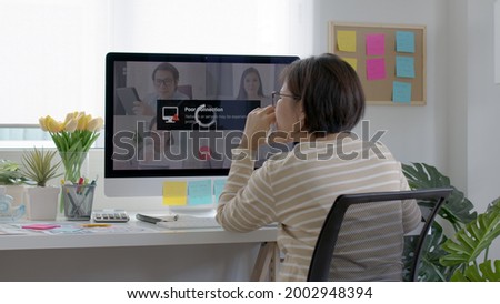 Back view mature asian woman employee work from home use computer desktop pc videocall webinar conference angry annoy in low poor unreliable bad wifi connection slow issue outage.