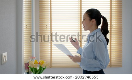 Young female leader, asia people lady or mba student happy standing smile look at in front of mirror pep talk for sale pitch hold paper document script public speak skill for job career self improve. Royalty-Free Stock Photo #2002948553