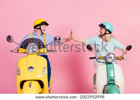 Photo of sweet funny grandmother grandfather riding motorcycle helmets high five arms together isolated pink color background