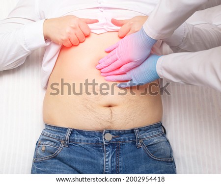 The doctor examines a patient who has abdominal pain. Pancreas inflammation concept, pancreatitis, close-up. Inflammation of the gallbladder and duodenum Royalty-Free Stock Photo #2002954418