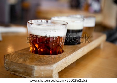 Three glasses with different types of beer on a table in a bar, photo with soft focus