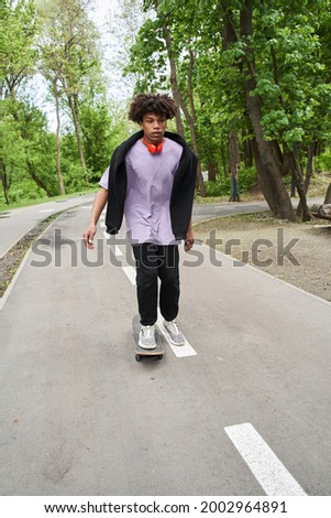 Man with curly hair practicing skateboarding while enjoying active rest at the urban road