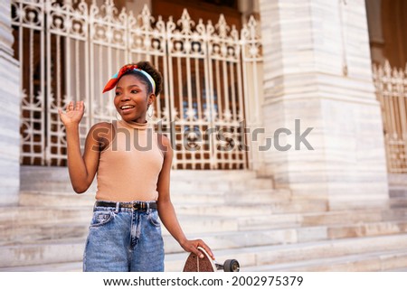 Happy african woman with skateboard. Young stylish woman with skateboard outdoors
