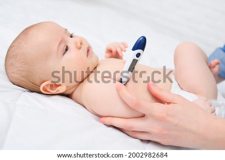 a baby with a thermometer under his armpit is measured by his mother's body temperature. Children's diseases. Royalty-Free Stock Photo #2002982684