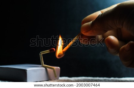 Concept of weakness, sadness, and loneliness. Image of a man-made matchstick. Burning matchstick man sitting alone without a partner. Matchstick art photography. Royalty-Free Stock Photo #2003007464