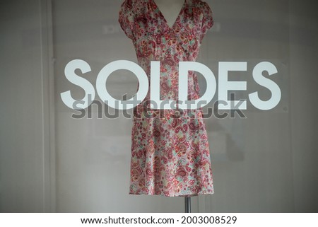 discount sign "SOLDES " in french,  the traduction of  (sales ) on window in french fashion store showroom on summer clothes background