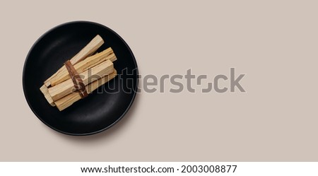 Palo Santo sticks tied in a bunch on a black plate. Top view. Organic holy tree incense from Latin America. Color photo close-up of natural frankincense.