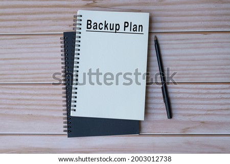 Backup plan text on notepad with wooden background. Business concept