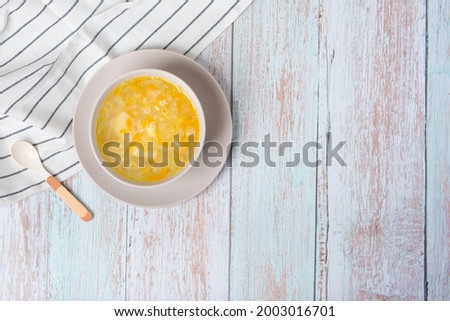 Healthy natural eco baby food. Children's soup made of carrots, onions, cabbage, potatoes in a plate and a spoon on a wooden background with copy space Royalty-Free Stock Photo #2003016701