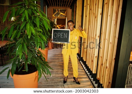 African american woman hold open welcome sign board in modern cafe coffee shop ready to service, restaurant, retail store, small business owner.
