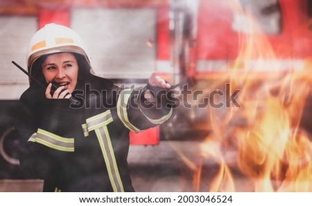 Firefighter in uniform using portable radio set near fire truck outdoors