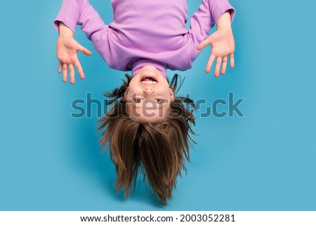 Portrait photo little girl hanging upside down isolated pastel blue color background
