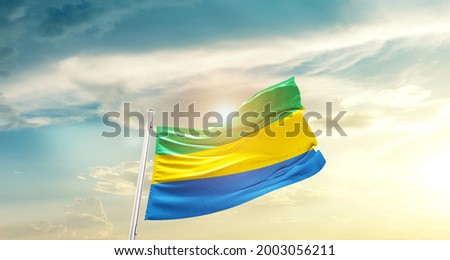 Gabon national flag waving in beautiful clouds. Royalty-Free Stock Photo #2003056211