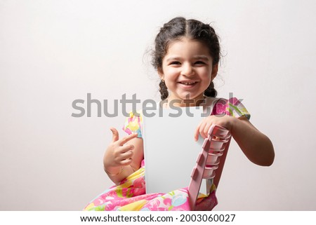 Happy little girl pointing to a story book with blank cover in front of her body, editable mock-up series template ready for your design, book cover selection path included.