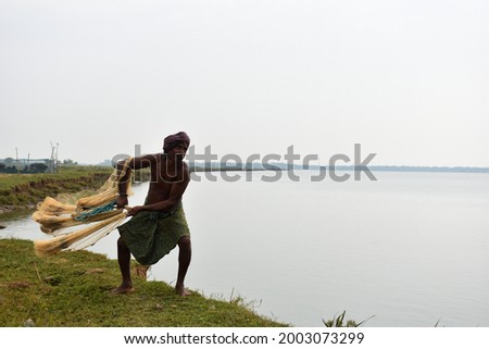 Indian Fisherman throwing net into the river Brahmani to caught fish