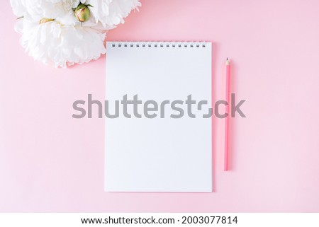 Blank notepad with pencil on pink background.