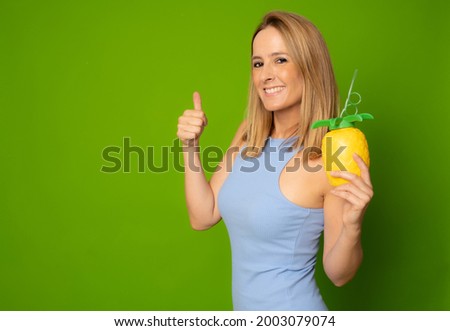 Happy woman wearing casual dress holding a cocktail, having fun isolated over green background