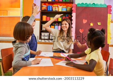 Kindergarten teacher and a child at high five in a painting course in preschool or kindergarten